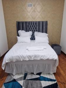 1 dormitorio con 1 cama grande con sábanas y almohadas blancas en Pinto City Motel en Kempton Park