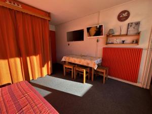 ein Hotelzimmer mit einem Tisch und einem roten Vorhang in der Unterkunft Studio Les Menuires, 1 pièce, 4 personnes - FR-1-452-190 in Les Menuires