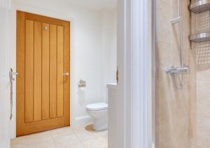 a bathroom with a toilet and a wooden door at Little Bourne in Tonbridge