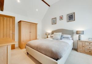a white bedroom with a bed and a wooden cabinet at Little Bourne in Tonbridge