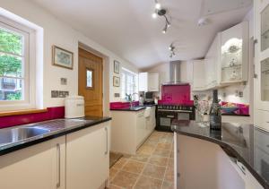 uma grande cozinha com armários brancos e electrodomésticos cor-de-rosa em Little Ponds em Cross in Hand