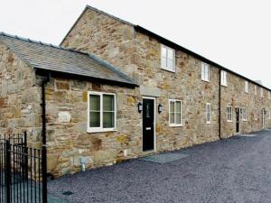 un antiguo edificio de piedra con una puerta y ventanas negras en Connah's Quay Park Farm Barns, en Connahs Quay