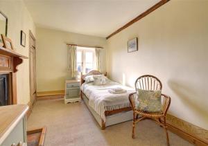 a bedroom with a bed and a chair and a window at Poppy Cottage in Bodham
