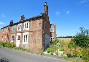 an old brick building on the side of a road at Poppy Cottage in Bodham