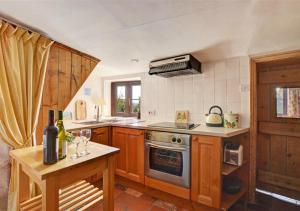 a kitchen with a stove and a table with wine glasses at Poppy Cottage in Bodham