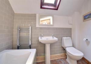 a bathroom with a sink and a toilet and a tub at Poppy Cottage in Bodham +6 photos