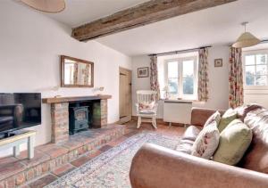a living room with a couch and a fireplace at Poppy Cottage in Bodham
