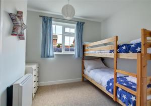 a bedroom with two bunk beds and a window at Crows Nest in Brancaster