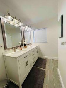 ein weißes Badezimmer mit einem Waschbecken und einem Spiegel in der Unterkunft Entire Deluxe Studio in Orlando near Disney Universal Studio Airpot and The Convention Center in Orlando