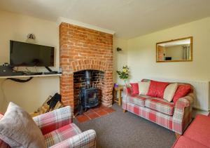 a living room with two couches and a brick fireplace at The Cottage in Hickling