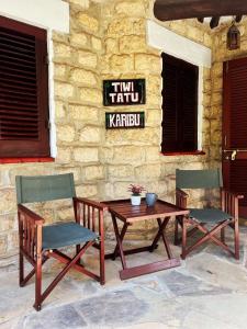 a table and two chairs and a table and a sign at Tiwi Tatu in Tiwi