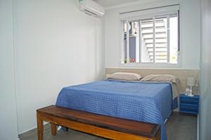 Un dormitorio con una cama azul y una ventana en Casa com 2 quartos à 200 m da da praia c/ churrasqueira, en Palhoça