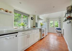 a kitchen with white cabinets and a tile floor at The Cottage in Hickling