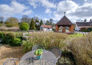 a table and chairs with a gazebo in a garden at Apple Tree Cottage in Poringland