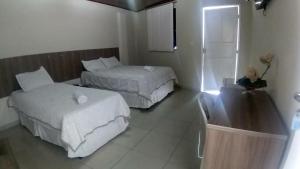 a hotel room with two beds and a refrigerator at Hotel Aracaju Express in Aracaju