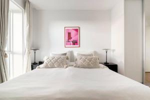 um quarto branco com uma grande cama branca com almofadas em Penthouse with amazing views of Copenhagen! em Copenhague