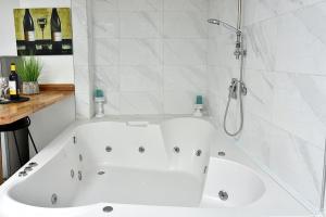 a white bath tub in a bathroom with a shower at סוויטת פנינת הים in Shelomi
