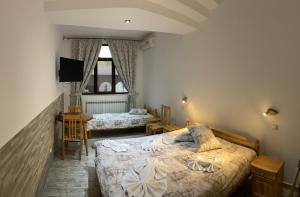 a bedroom with two beds and a flat screen tv at Guesthouse Hitar Petar in Gabrovo