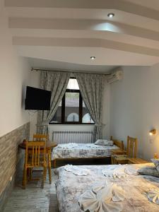 a bedroom with two beds and a tv on the wall at Guesthouse Hitar Petar in Gabrovo