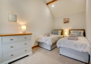 a bedroom with two beds and a dresser with two lamps at Green Farm Barns - The Old Dairy in Brundall