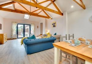 a living room with a blue couch and a table at Green Farm Barns - The Old Dairy in Brundall