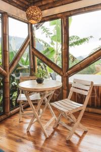 The Coffee Club Campestre في Chinchiná: طاولة وكراسي في غرفة بها نوافذ
