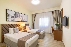 pokój hotelowy z 2 łóżkami i telewizorem w obiekcie Golden Sands Hotel Apartments w Dubaju