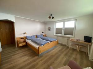 sypialnia z łóżkiem, biurkiem i oknem w obiekcie Pension Hilde w mieście Sulzberg