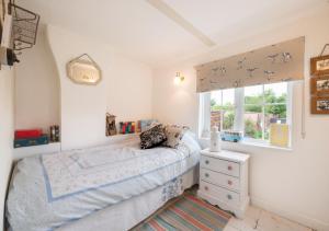 a small bedroom with a bed and a window at Little Rosa in Wells next the Sea