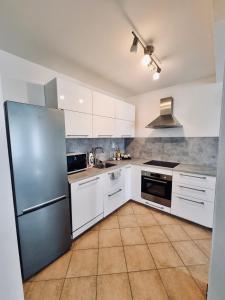 a kitchen with white cabinets and a stainless steel refrigerator at Apartment Banska - City Centre & Free Parking in Banská Bystrica