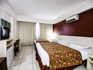 a hotel room with two beds and a flat screen tv at Flat Le Jardin Suites in Caldas Novas