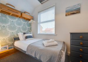sypialnia z łóżkiem z komodą i oknem w obiekcie Star Cottage w mieście Holt