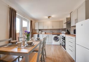 a kitchen with a wooden table with chairs and a dining room at The Cart Lodge in Chedgrave