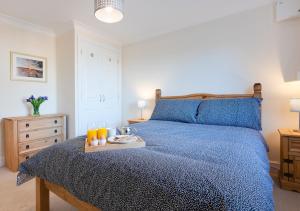 Schlafzimmer mit einem blauen Bett und einem Tablett mit Orangensaft in der Unterkunft The Workshop in Chedgrave