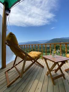 a rocking chair and a table on a deck at DENGEKORU Wildlife & Glamping in Mudurnu