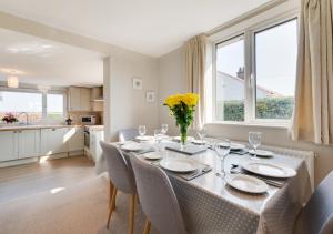 a dining room with a table with chairs and a kitchen at Journeys End in Ringstead