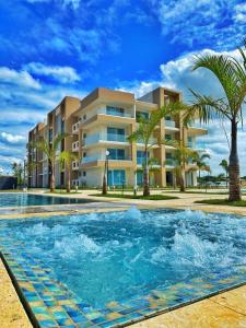 a swimming pool in front of a building with palm trees at Beach front and golf paradise. Playa Nueva Romana in San Pedro de Macorís