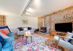 a living room with a brick wall and a tv at Mill Farm Barn in Walcott