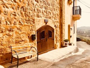 a bench in front of a building with a wooden door at Brooklyn Farmhouse in Żebbuġ