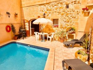 a swimming pool in a yard with a table and chairs at Brooklyn Farmhouse in Żebbuġ