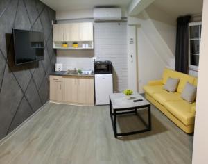 a living room with a yellow couch and a kitchen at Finesi Apartments 2 in Ohrid