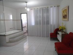 sala de estar con bañera y silla roja en Hotel Silveira, en Bambuí