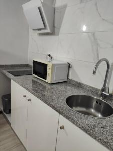 a kitchen counter with a sink and a microwave at CIH - Constituição Invicta Home in Porto