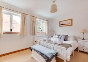 a white bedroom with a bed and a window at Egg Cottage in Holt