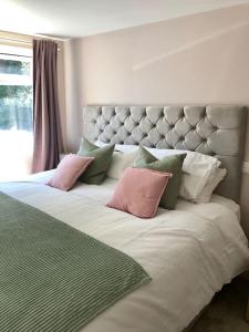 a large bed with pink and green pillows on it at Quiet and cosy flat, close to Bath Centre in Bath