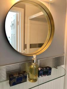a mirror over a bathroom sink with a bottle of soap at Cosy Flat, close to Bath Rugby and City Centre in Bath