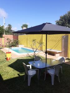 einen Tisch und Stühle unter einem Sonnenschirm neben einem Pool in der Unterkunft La Candela 1 casa in Villa Lonca