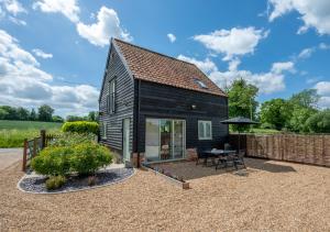 a black tiny house with a patio and a table at The Cart Shed in Thurton