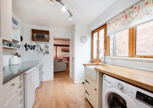 a kitchen with a washer and dryer in it at Poppy Cottage in Briston