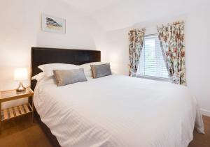 a bedroom with a large white bed and a window at Poppy Cottage in Briston